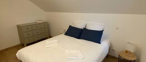 A bedroom with a bed, a nightstand, a dresser, and a ceiling light.