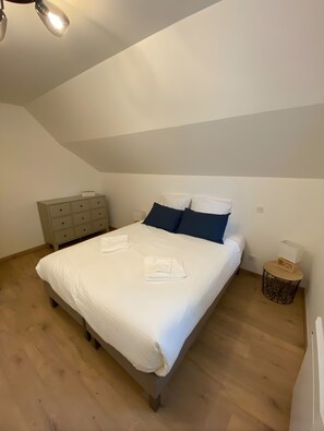A bedroom with a bed, a nightstand, a dresser, and a ceiling light.