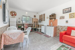 A compact living space with a dining area, a kitchenette, a red sofa, and various wall decorations.