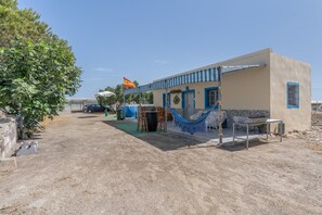 A building with a blue-striped awning, a flag, and a hammock.