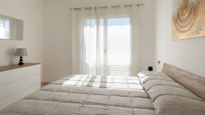 A bedroom with a bed, a bedside table, a lamp, a window with curtains, and a wall art piece. - La Dimora Molara by Wonderful Italy (Olbia)