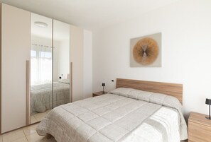 A bedroom with a bed, a nightstand, a mirror, and a wall-mounted artwork. - La Dimora Tavolara by Wonderful Italy (Olbia)