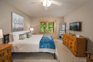 A bedroom with a bed, dresser, TV, window, and artwork. - The Bear Den (Boone)