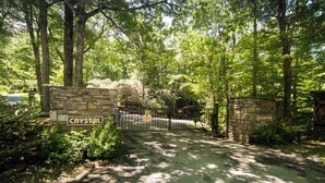 Una puerta de piedra con el rótulo 'CRYSTAL', un sendero pavimentado y una zona boscosa.