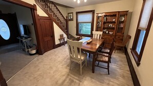 Un comedor con una mesa y sillas de madera, una escalera y una estantería.