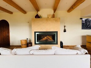 Ein Wohnzimmer mit Kamin, Holzbalken, einer Couch und einer Tür.
