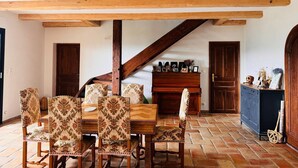 A dining area with a wooden table and chairs, a staircase, and a piano. - Magnificent Villa with Panoramic Views & Pool (Fabras)