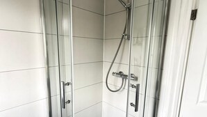 A glass-enclosed shower stall with a handheld showerhead and a wall-mounted faucet. - modern studio flat with free parking near tube (Ruislip)