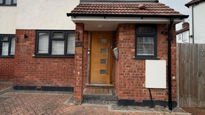 A two-story residential building with a brick facade, a tiled roof, and a front door with a small porch. - modern studio flat with free parking near tube (Ruislip)