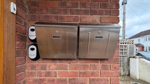 A brick wall with two metallic intercoms and a door. - modern studio flat with free parking near tube (Ruislip)
