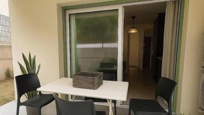 A patio with a table and chairs, a sliding glass door, and potted plants. - Ground-floor apartment in a quiet residence (Corte)