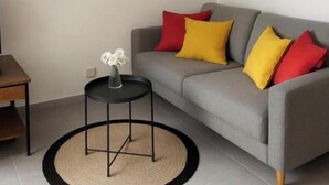 A living room with a grey sofa, red and yellow cushions, a small round table with a vase, and abstract paintings on the walls. - Ground-floor apartment in a quiet residence (Corte)