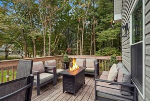 A fire table surrounded by comfy seating on the deck sets the scene for cozy evenings, perfect for sharing stories and warming up under the trees. - Stay & Play | Poconos Lake • Hot Tub • Sauna (Albrightsville)