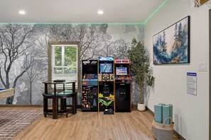 Ein Zimmer mit Spielhallenspielen, einem Glastisch, einem Gemälde und einem Sicherheitsschild.