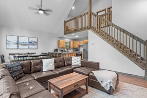 A modern living room with a sectional sofa, wooden coffee table, and a staircase with wooden railings. - Sleeps 16 | Hot Tub, Arcade & Resort Amenities (Albrightsville)