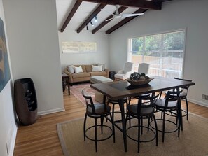 Ein Essbereich mit Holztisch und Stühlen, einer Couch und einem Fenster mit Jalousien.