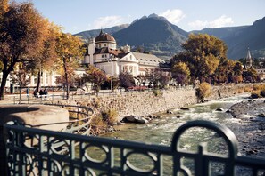 A river with a bridge, a building with a dome, and mountains in the background. - Leiter Living high-quality apartment (Algund)