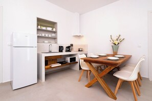 Eine moderne Küche mit weißen Schränken, einer eingebauten Mikrowelle und einem Essbereich mit einem Holztisch und weißen Stühlen.