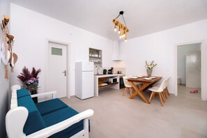 Eine moderne Küche mit weißen Schränken, einem weißen Kühlschrank und einem Essbereich mit Holztisch und weißen Stühlen.