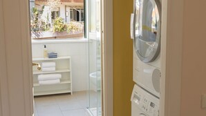 A laundry room with a washing machine, a dryer, and a glass shower enclosure. - TrastevereHome - Quiet 3 bedroom Home in Trastevere with Elevator (Rome)
