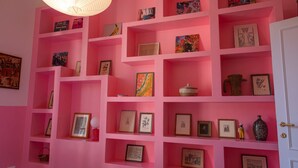 A pink room with multiple shelves displaying framed pictures and small decorative items. - TrastevereHome - Quiet 3 bedroom Home in Trastevere with Elevator (Rome)