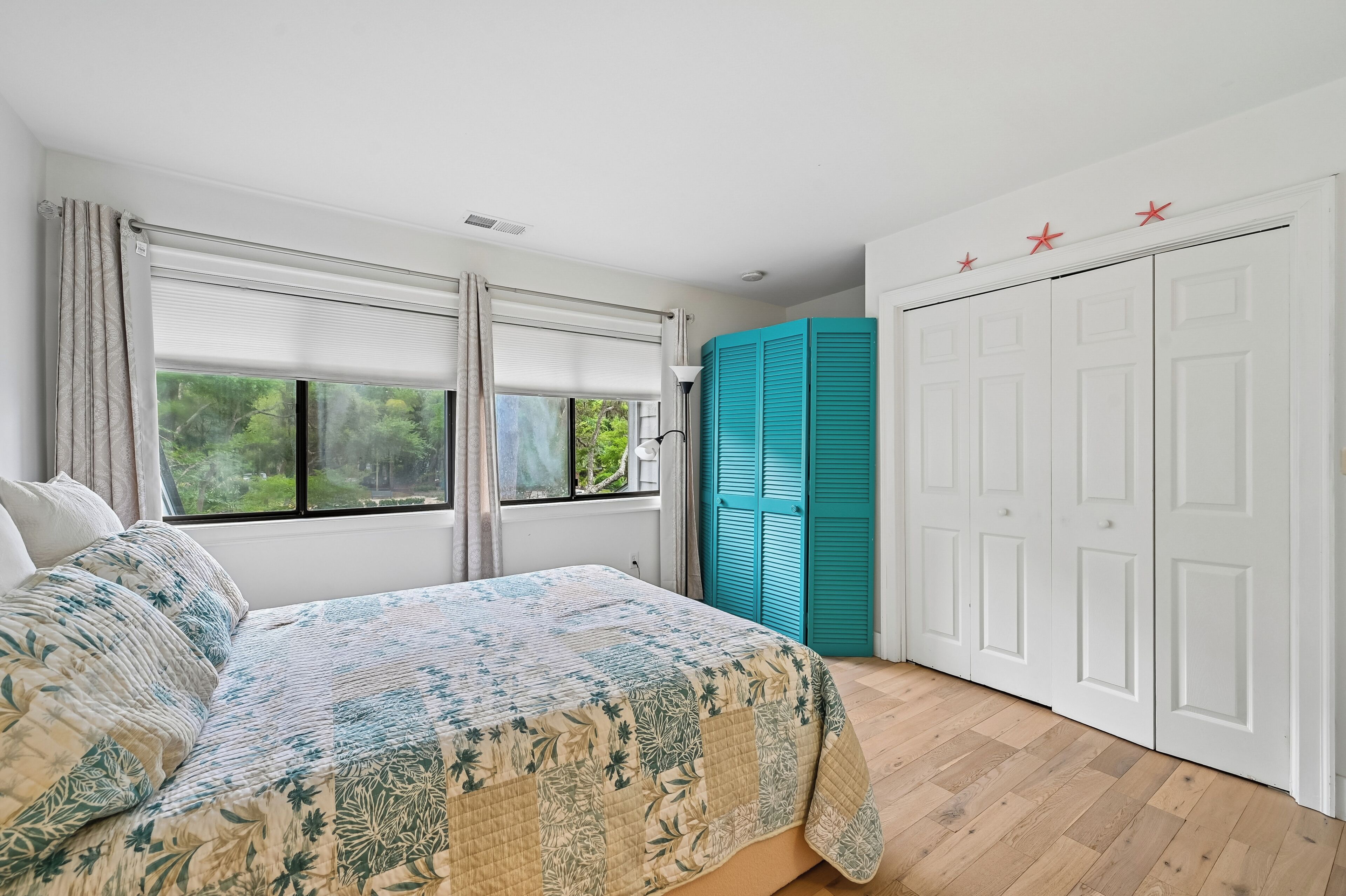 Un dormitorio con cama, ventana con cortinas, armario y una puerta decorada con estrellas.