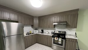 Uma cozinha moderna com armários de madeira, eletrodomésticos de aço inoxidável, micro-ondas, cafeteira, torradeira e forno.