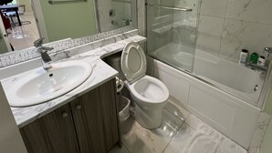 Um banheiro moderno com toucador de mármore, vaso sanitário e chuveiro com divisória de vidro.