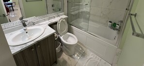 Ein Badezimmer mit Marmorwaschbecken, Toilette und einer Duschkabine.