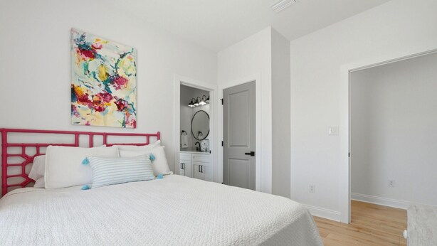 A bedroom with a bed, a dresser, a mirror, and a door. - Grenadine Dreams (Gulf Shores)
