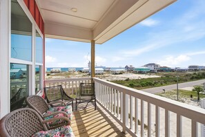 Ein Balkon mit Korbstühlen und Blick auf Strand und Häuser.