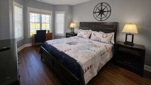 A bedroom with a bed, a desk, a chair, a ceiling fan, and a wall clock. - Sea Bound | Golf Getaway + Pool | Myrtle Beach (Myrtle Beach)
