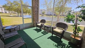 A covered outdoor seating area with wicker chairs, a small table, and a potted plant. - Sea Bound | Golf Getaway + Pool | Myrtle Beach (Myrtle Beach)