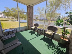 A covered outdoor seating area with wicker chairs, a small table, and a potted plant. - Sea Bound | Golf Getaway + Pool | Myrtle Beach (Myrtle Beach)
