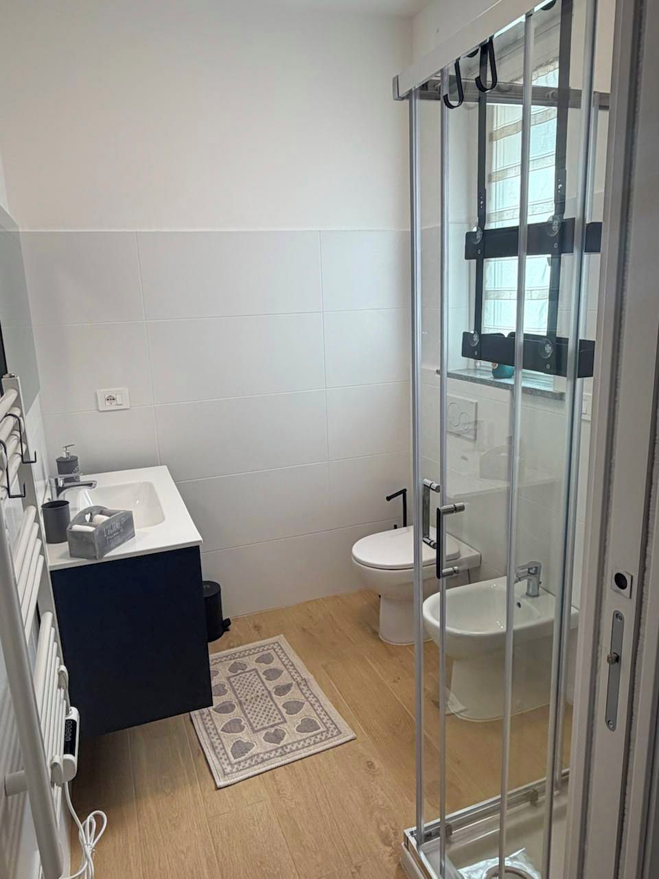 Un baño moderno con cabina de ducha de vidrio, un lavamanos blanco y un inodoro.
