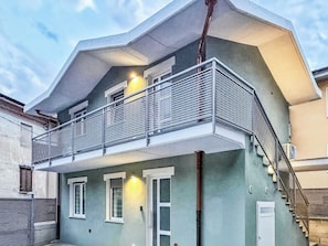 A two-story building with a balcony, a staircase, and a door. -  Casa Cavour - In Val di Susa con Parcheggio Moto (Bruzolo)
