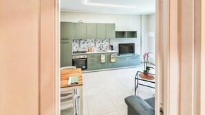 A modern kitchen with green cabinets, a microwave, and a television. -  Casa Cavour - In Val di Susa con Parcheggio Moto (Bruzolo)