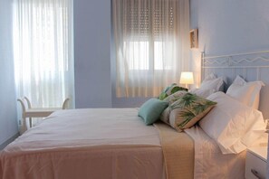 Ein Schlafzimmer mit Bett, Kissen, Nachttisch, Lampe und Stuhl.