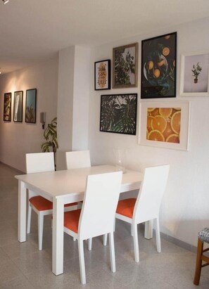 Ein Essbereich mit einem weißen Tisch und Stühlen, umgeben von gerahmten Kunstwerken an den Wänden.