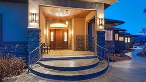 Een modern huis met een stenen gevel, een houten deur en een trap die naar de ingang leidt.