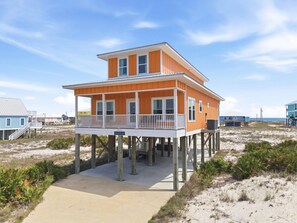 A two-story beach house with a balcony, wooden deck, and a sandy beach setting. - Tangerine Dream (Gulf Shores)