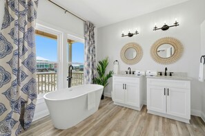 Ein Badezimmer mit einer freistehenden Badewanne, zwei Waschbecken und verzierten Spiegeln.