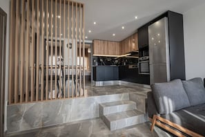 A modern kitchen with a central island, built-in appliances, and a dining area with a wooden partition.