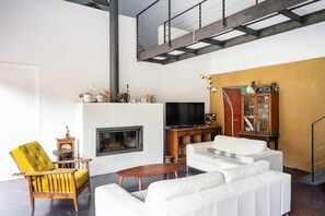 Ein modernes Wohnzimmer mit Kamin, weißem Sofa, gelbem Sessel und Fernseher.