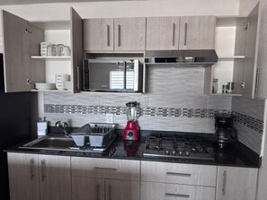 Eine moderne Küche mit Edelstahlgeräten, Holzschränken und einer schwarzen Arbeitsplatte.