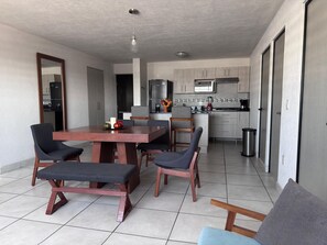 Eine moderne Küche mit Essbereich, inklusive Tisch mit Stühlen und einer Bank, einem Kühlschrank und einer Mikrowelle.