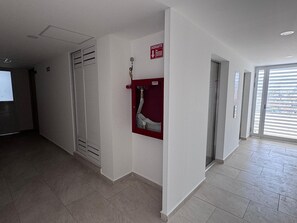 Ein Flur mit einem Hydranten, einem roten Feuerschutzschild und einer Tür.