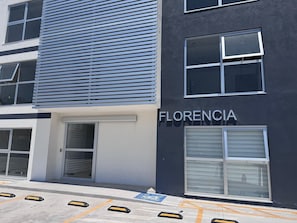 Ein Gebäude mit der Aufschrift 'FLORENCIA' an der Fassade, großen Fenstern und einer Tür mit einem Metallgitter.