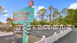 A motel sign with amenities listed, including TV, heated pool, A/C, and Wi-Fi. - Violet Valentino | Purple Boutique Retreat (Port Saint Joe)