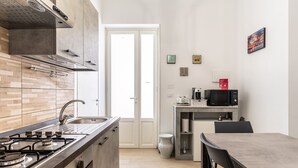 A modern kitchen with a gas stove, stainless steel appliances, a microwave, and a dining area with a table and chairs. - La Capinera by Wonderful Italy (Noto)